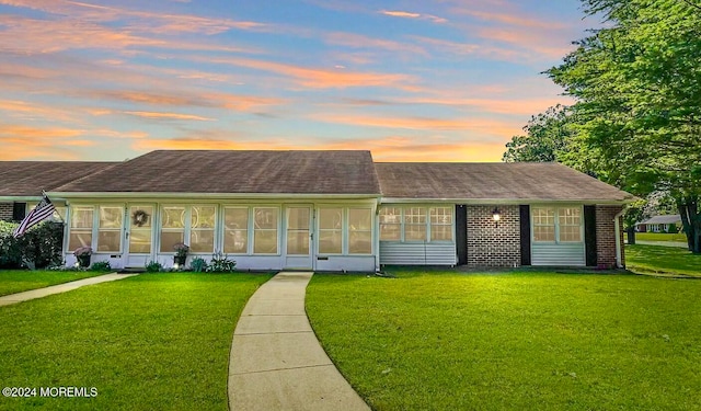 view of front of property with a sunroom and a yard