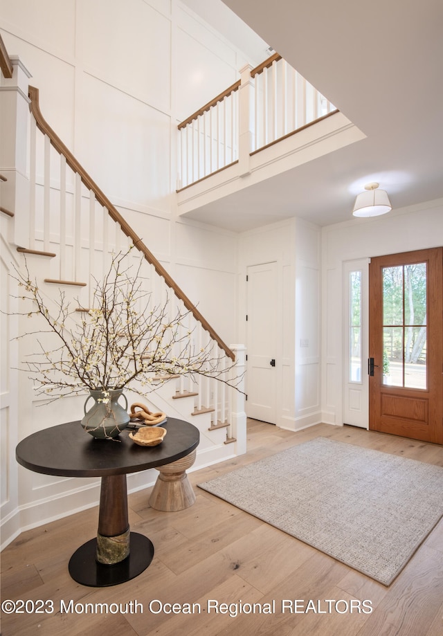 entrance foyer featuring a towering ceiling and wood-type flooring