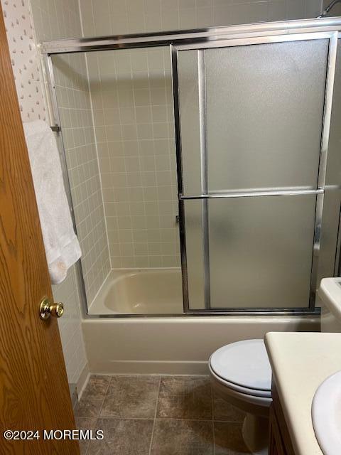 full bathroom with tile patterned floors, vanity, toilet, and enclosed tub / shower combo