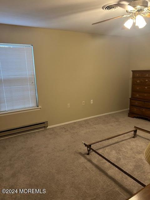 unfurnished bedroom featuring ceiling fan, carpet floors, and baseboard heating