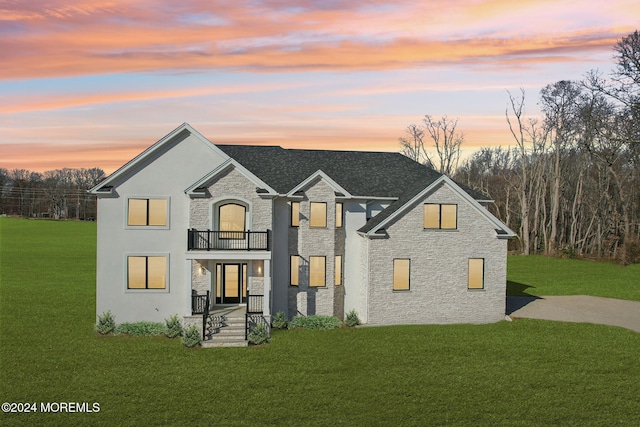 view of front of home featuring a balcony and a lawn