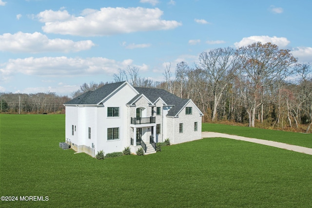 view of front of property featuring a balcony, cooling unit, and a front yard