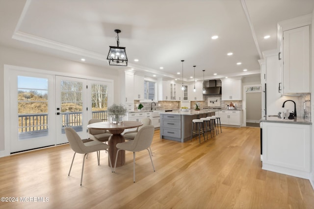 dining area featuring french doors, crown molding, sink, light hardwood / wood-style flooring, and a notable chandelier