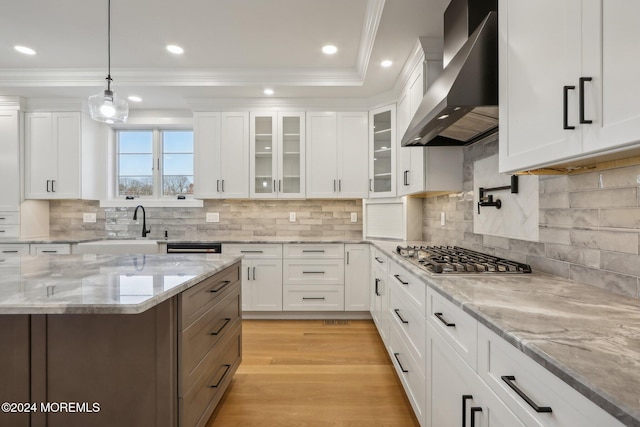 kitchen featuring white cabinets, light wood-type flooring, wall chimney range hood, and stainless steel gas stovetop