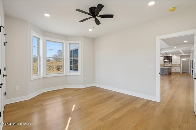 empty room with ceiling fan and light hardwood / wood-style floors