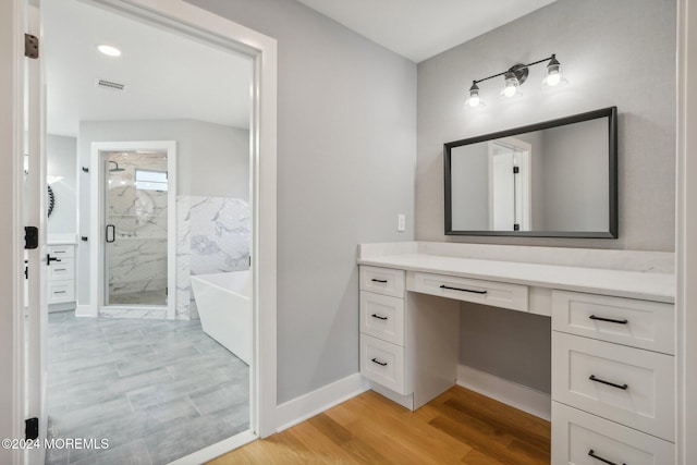 bathroom featuring hardwood / wood-style flooring, vanity, and separate shower and tub