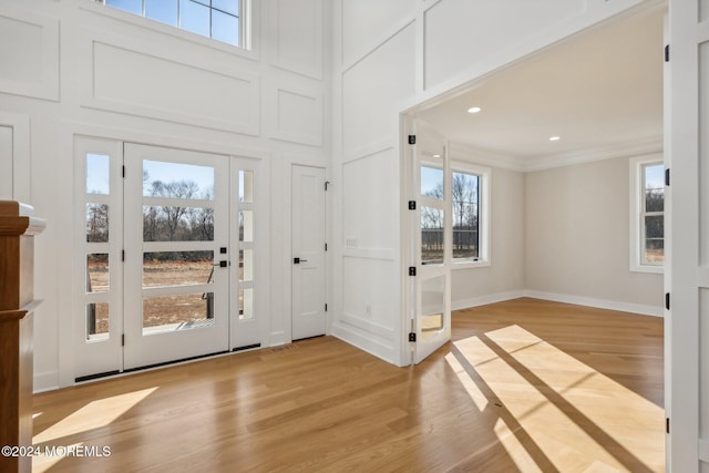 foyer entrance with crown molding, plenty of natural light, and light wood-type flooring