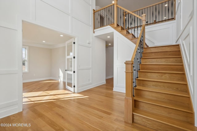 staircase with wood-type flooring and crown molding