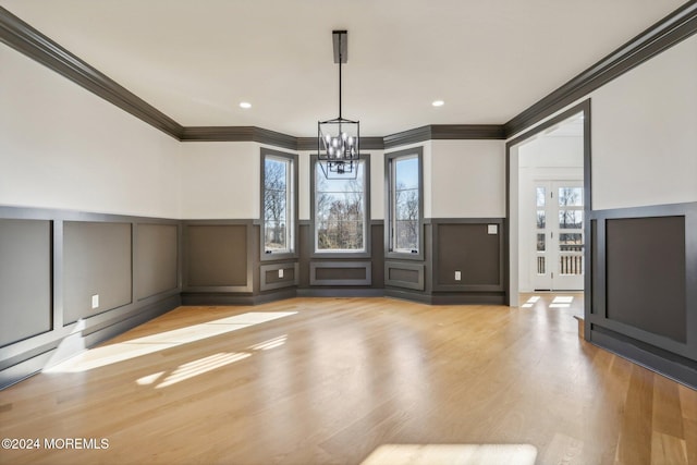 unfurnished living room featuring crown molding, light hardwood / wood-style flooring, and a chandelier