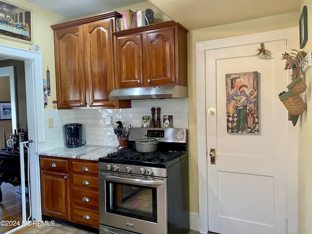 kitchen with light stone countertops, tasteful backsplash, and stainless steel gas range