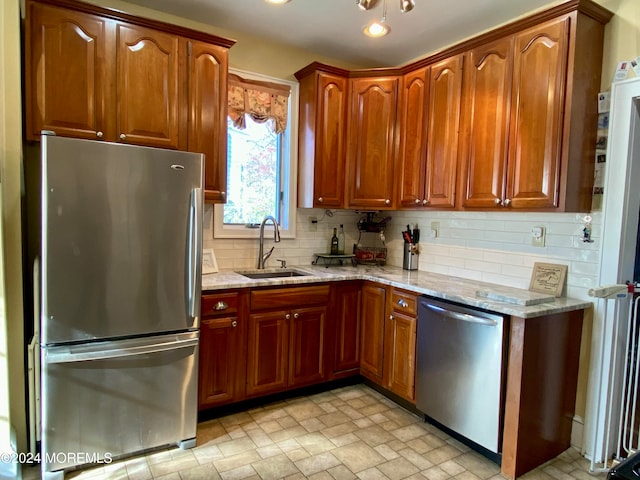 kitchen with appliances with stainless steel finishes, tasteful backsplash, light stone counters, and sink