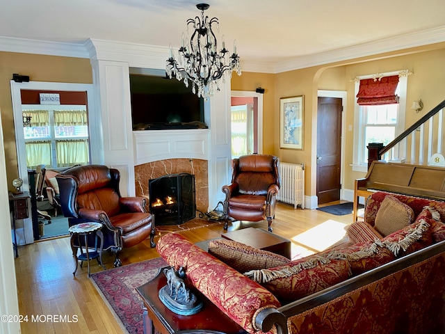 living room with light hardwood / wood-style floors, radiator heating unit, ornamental molding, and a wealth of natural light