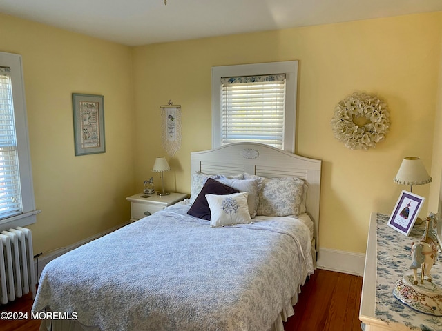 bedroom with radiator heating unit and dark hardwood / wood-style flooring