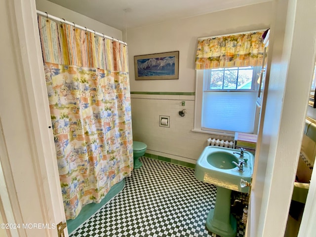 bathroom with toilet and tile walls