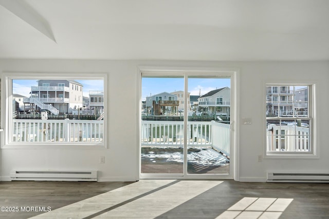 doorway to outside featuring a water view, a baseboard heating unit, and plenty of natural light