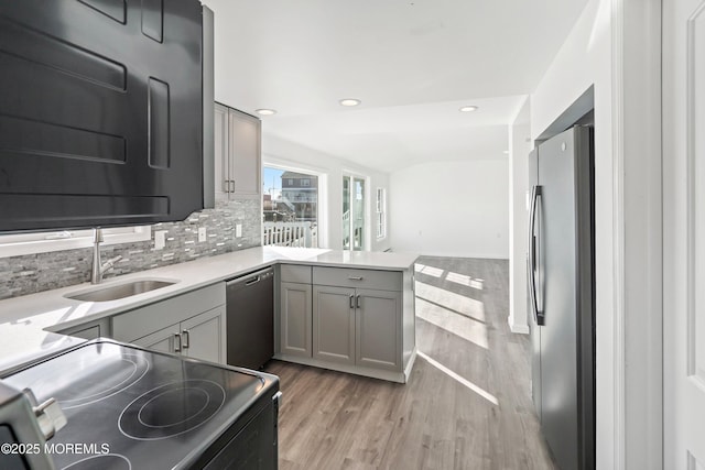 kitchen with gray cabinetry, stainless steel appliances, sink, and hardwood / wood-style flooring