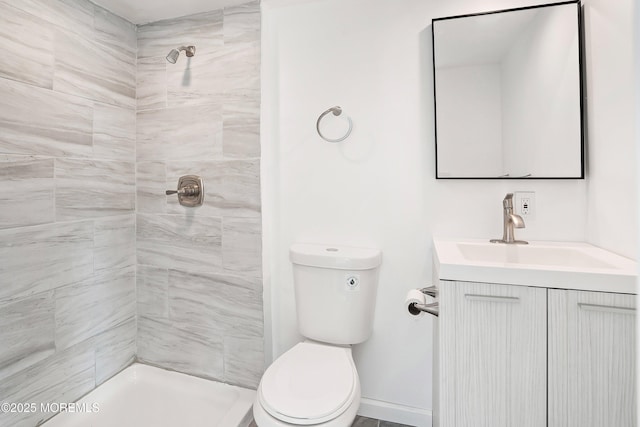 bathroom with a tile shower, vanity, and toilet