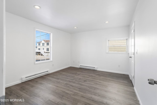 unfurnished room with dark hardwood / wood-style flooring and a baseboard heating unit