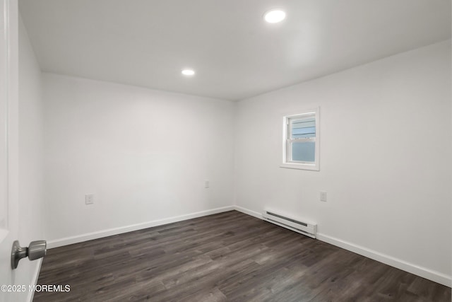 empty room featuring baseboard heating and dark hardwood / wood-style flooring