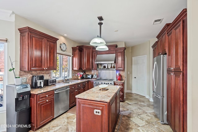 kitchen featuring sink, extractor fan, decorative light fixtures, a kitchen island, and appliances with stainless steel finishes