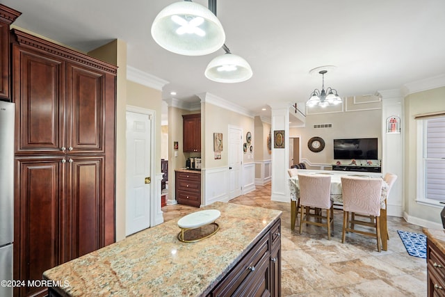 kitchen with decorative light fixtures, an inviting chandelier, light stone counters, and ornamental molding