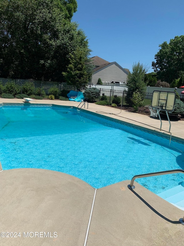 view of swimming pool featuring a diving board and a patio area