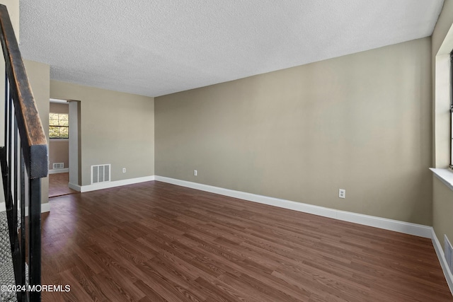 empty room featuring dark hardwood / wood-style flooring and a textured ceiling