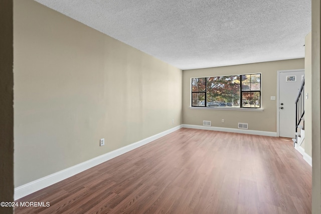 unfurnished room featuring a textured ceiling and light hardwood / wood-style floors