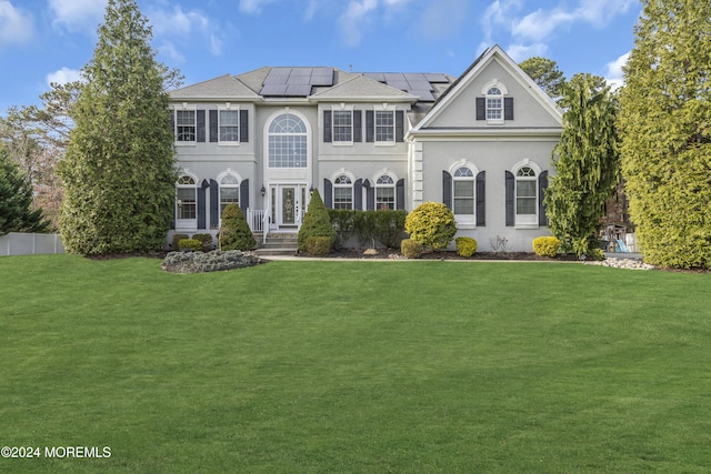 view of front of home featuring a front lawn and solar panels