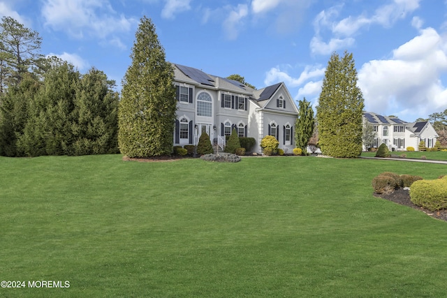 view of front of property featuring a front yard and solar panels