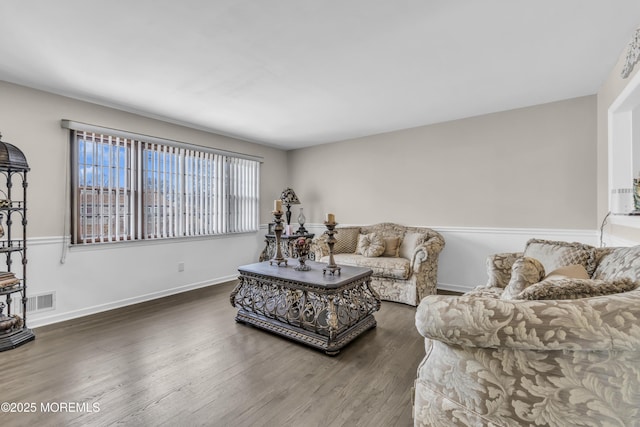 living room with baseboards, visible vents, and wood finished floors