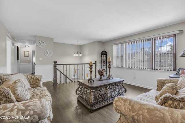 living room with a notable chandelier, wood finished floors, attic access, and baseboards