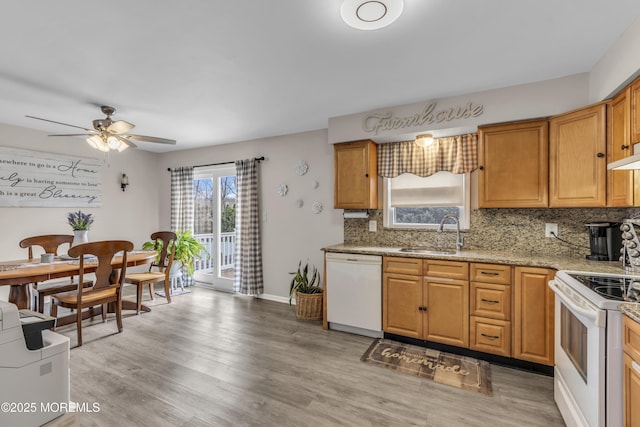 kitchen featuring white appliances, decorative backsplash, light stone countertops, light wood-type flooring, and a sink