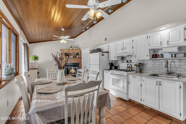 dining area with light tile patterned floors, visible vents, a tiled fireplace, ceiling fan, and wooden ceiling