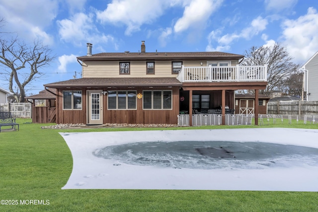 back of property with a storage shed, a lawn, a chimney, an outbuilding, and fence