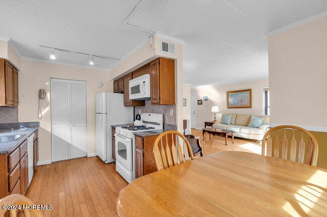 kitchen with backsplash, a textured ceiling, white appliances, and light wood-type flooring