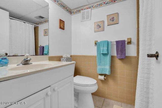 bathroom with tile patterned flooring, vanity, tile walls, and toilet