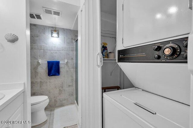 bathroom with tile patterned floors, vanity, a shower with shower door, and stacked washer / dryer