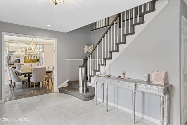 stairs with a textured ceiling and a notable chandelier