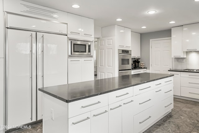 kitchen with built in appliances, a center island, and white cabinets