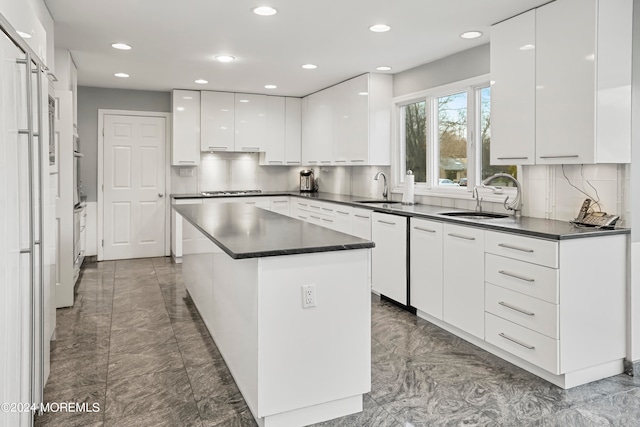 kitchen with decorative backsplash, white cabinetry, sink, and a center island