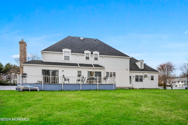 rear view of house featuring a lawn and a deck