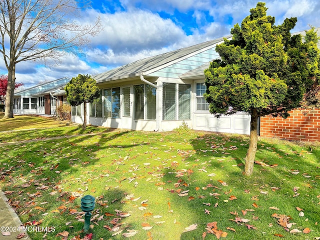 view of home's exterior with a yard and a sunroom