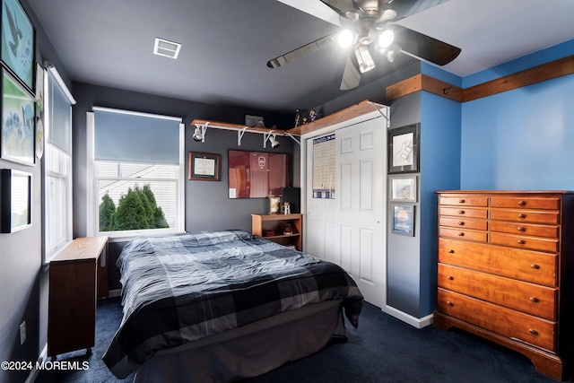 bedroom featuring dark colored carpet, a closet, and ceiling fan