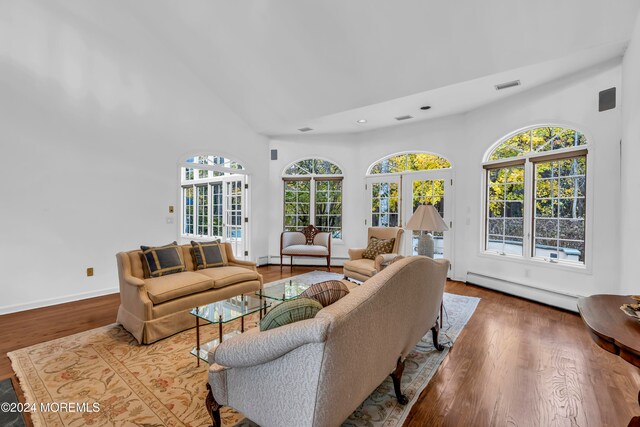 living room with baseboard heating, hardwood / wood-style floors, high vaulted ceiling, and a healthy amount of sunlight