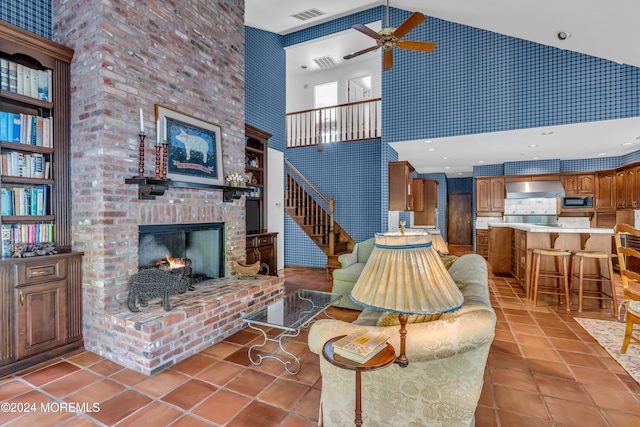 living room featuring ceiling fan, light tile patterned flooring, high vaulted ceiling, and a brick fireplace