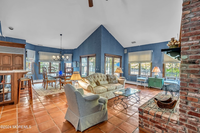 tiled living room with ceiling fan with notable chandelier and high vaulted ceiling