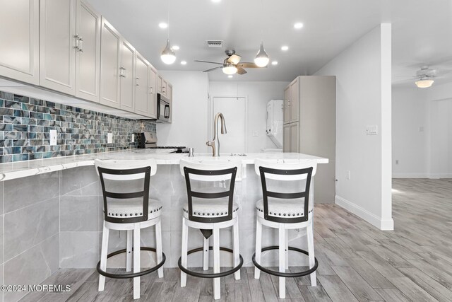 kitchen featuring light stone countertops, light hardwood / wood-style flooring, ceiling fan, and stainless steel appliances