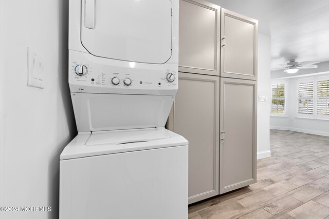 clothes washing area with ceiling fan, stacked washer and dryer, cabinets, and light hardwood / wood-style floors