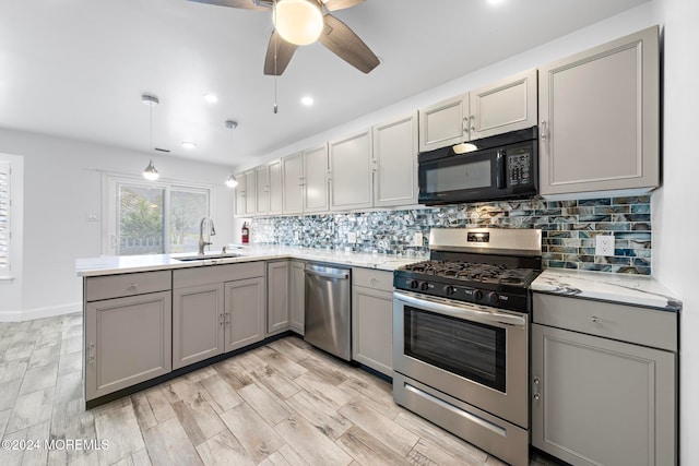 kitchen featuring kitchen peninsula, stainless steel appliances, sink, light hardwood / wood-style flooring, and gray cabinets